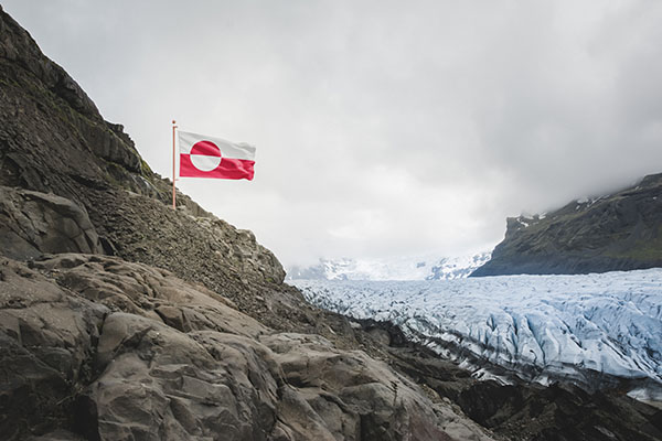 Greenland national flag above a rocky Arctic glacier