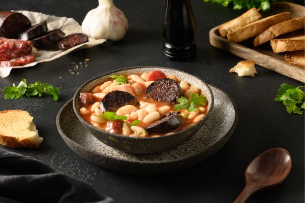 Fabada Asturiana: A rich, slow-cooked white bean stew featuring "compango" (chorizo, morcilla blood sausage, and bacon).