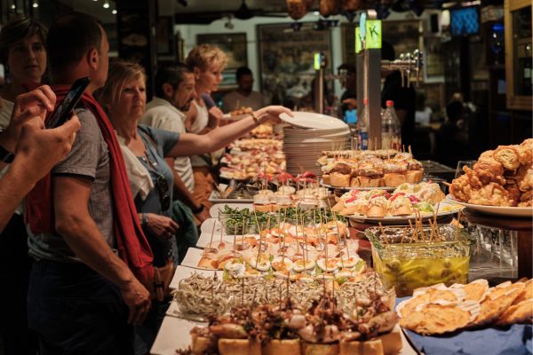 San Sebastian> Tourists watch and eat the pintxos from the bar.