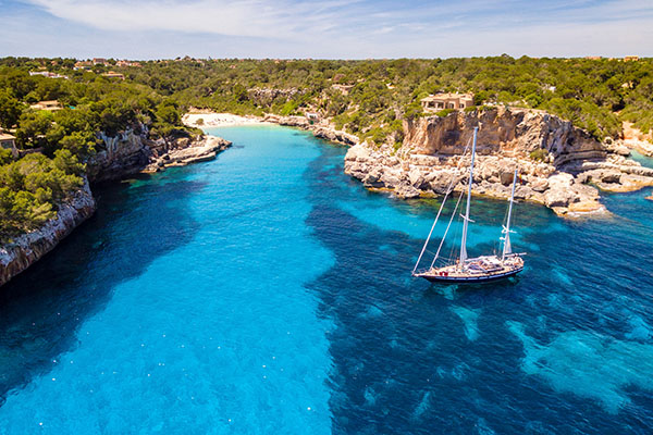 Sailboat anchored in Cala Llombards, Santanyí, Mallorca with turquoise water and rocky cove